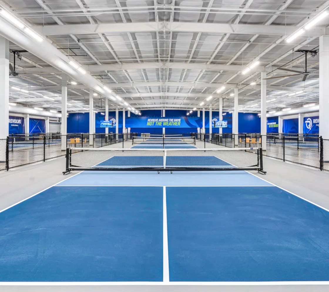 Indoor pickleball courts in a large facility illuminated by Brite Court LED high-bay lighting